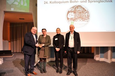 Vier Personen lächeln in die Kamera