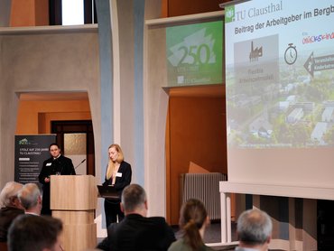 Rednerinnen stehen vor den Zuschauenden