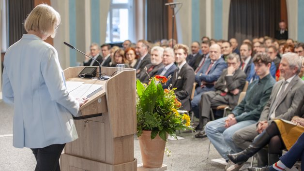 Rednerin von hinten fotografiert vor einer Gruppe Personen im Kuppelsaal der Aula Academica